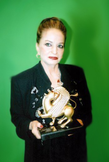 A woman holding an award in front of a green background.