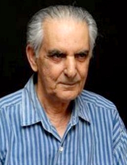 A man with grey hair and wearing a blue striped shirt.