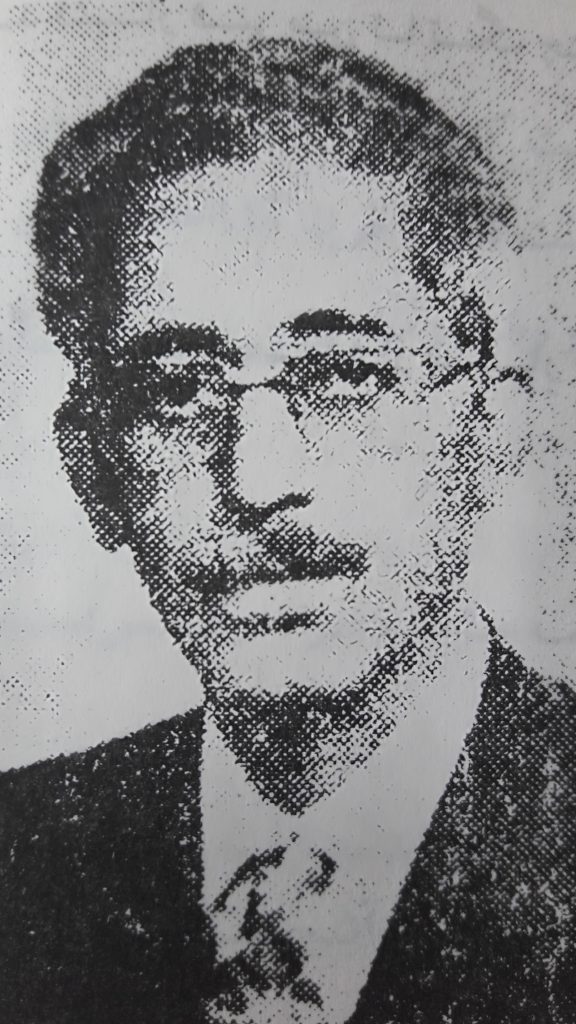 A black and white photo of a man in glasses.
