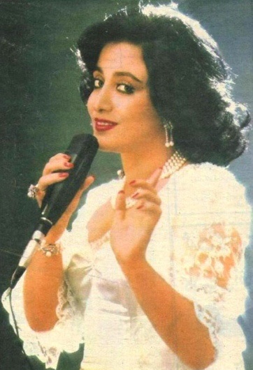 A woman holding a microphone and wearing white.