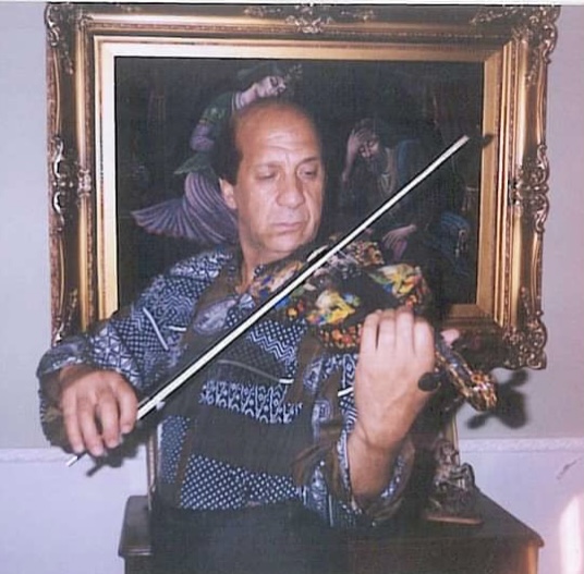 A man playing the violin in front of a painting.