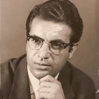 A man with glasses and a suit is sitting down