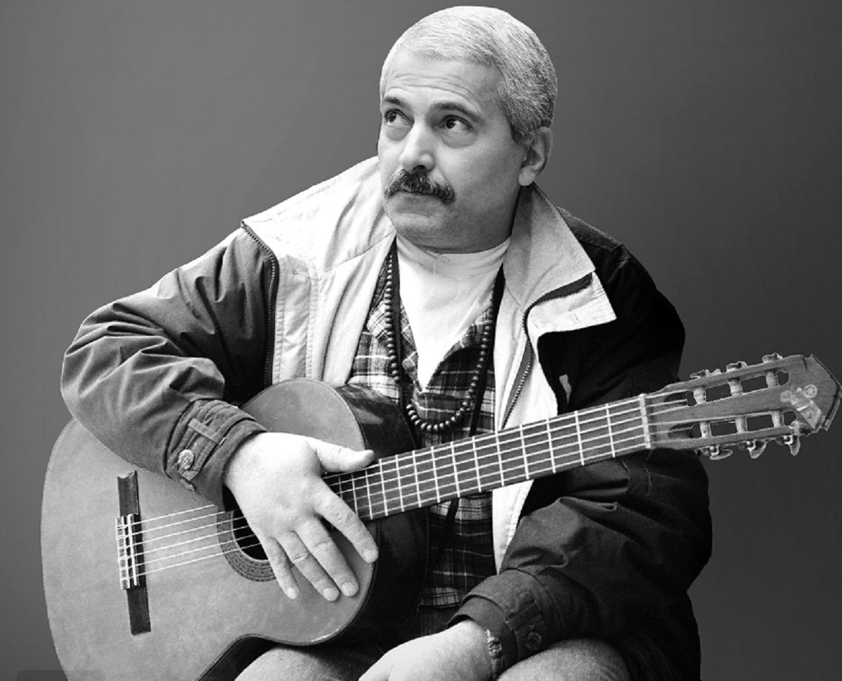A man sitting down with a guitar in his lap.