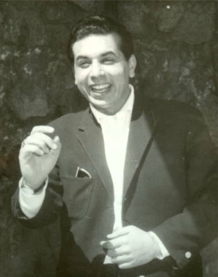 A man in suit and tie holding a cigarette.