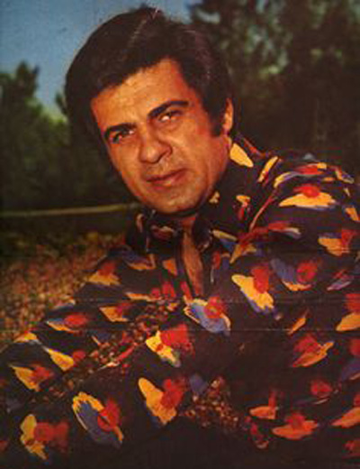 A man in colorful shirt holding a violin.